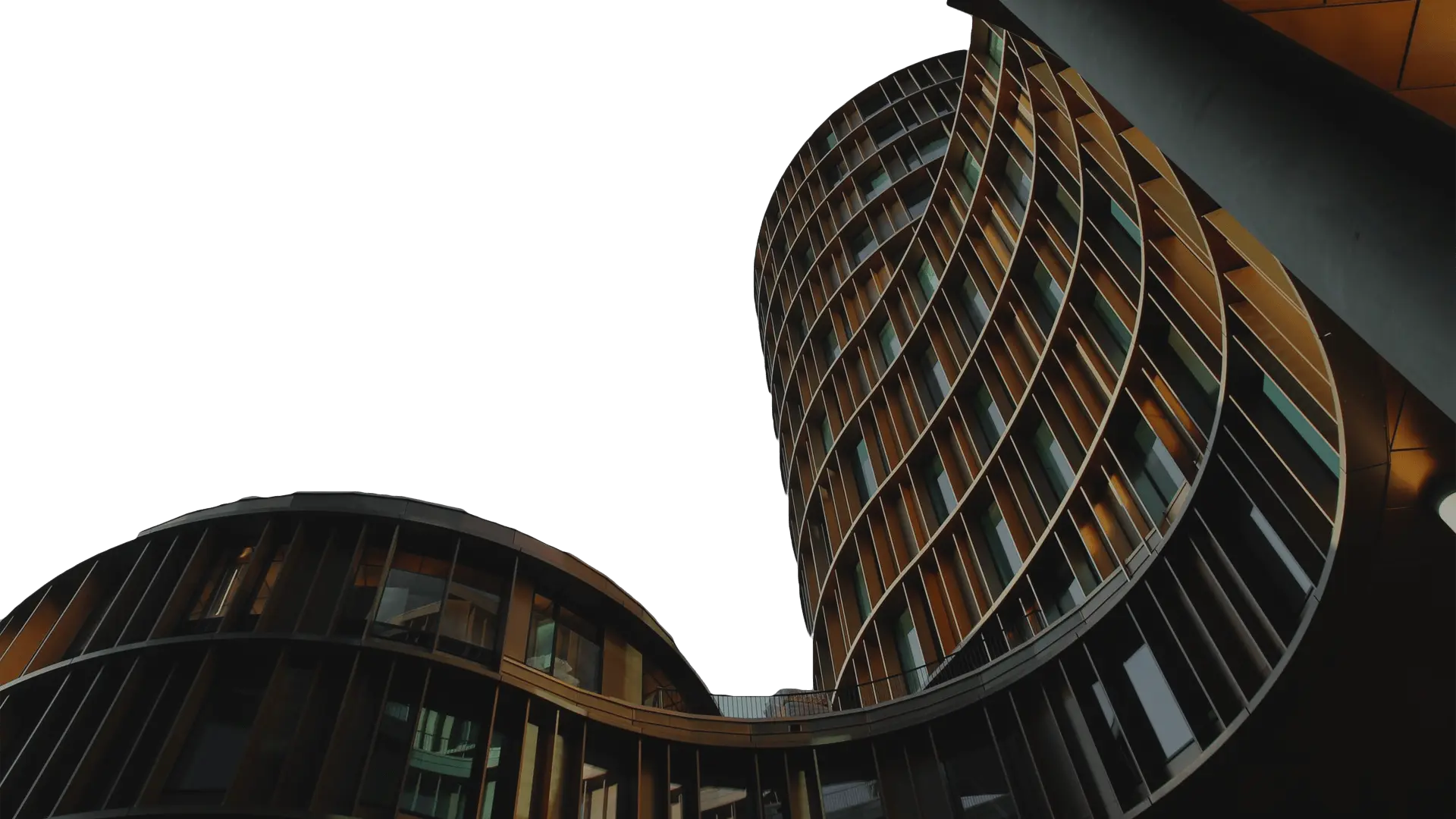 Modern circular office building with a curved metal facade and glass windows against a dark sky.